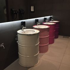 a row of pink and white buckets sitting next to each other in a bathroom