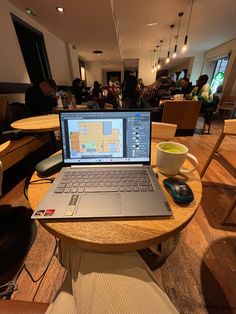 an open laptop computer sitting on top of a wooden table next to a coffee cup