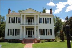 a large white house sitting on top of a lush green field