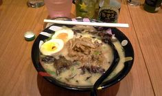 a bowl of soup with an egg on top and chopsticks next to it