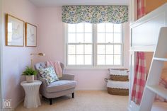 a baby's room with pink walls and floral curtains on the window sill