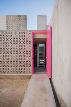 an entrance to a building with a pink door on the outside and white walls behind it