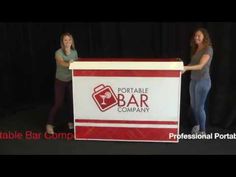 two women standing behind a sign that says portable bar company