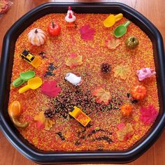 a black tray filled with lots of different types of fall decorations on top of a wooden table