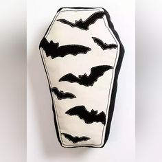 a white and black pillow with bats on it's side, hanging from the wall