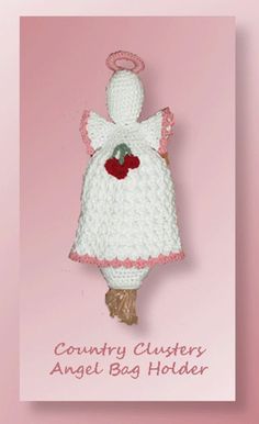 a crocheted doll hanging on a pink background with the words country clusters angel bag holder