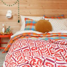 a bedroom with wood walls and colorful bedding