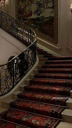 an ornate staircase with red carpeting and rugs on the riser, leading to a painting