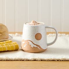 a mug sitting on top of a table next to bread