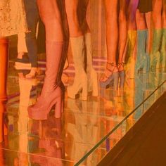 several women's legs in high heeled shoes are reflected in the glass floor