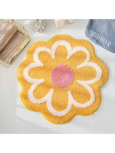 a yellow flower rug sitting on top of a white table next to a blue towel