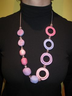 a woman wearing a black shirt and pink and blue necklace with circles on the front