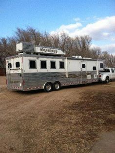 an rv parked on the side of a dirt road next to a white pickup truck