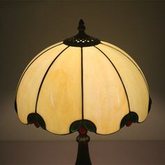 a stained glass lamp on a table with a white wall in the backround