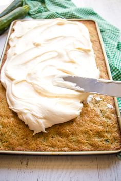 a person is spreading icing on a cake with asparagus in the background