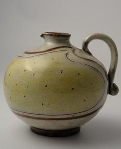 a white and brown vase sitting on top of a table