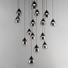 a bunch of lights that are hanging from the ceiling in front of a gray wall