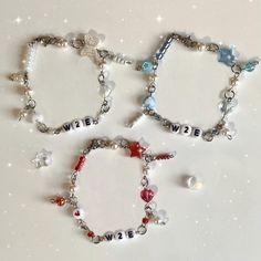 three bracelets with beads and charms are shown on a white surface, one has the word love written in small letters