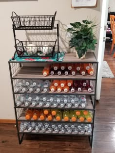 a metal shelf filled with lots of drinks next to a potted plant on top of a hard wood floor