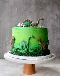 there is a green cake decorated with dinosaurs on it