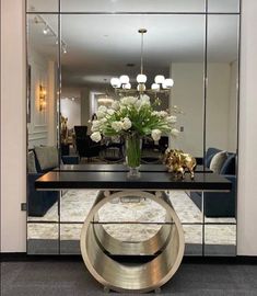 a large mirror sitting on top of a table next to a vase filled with flowers