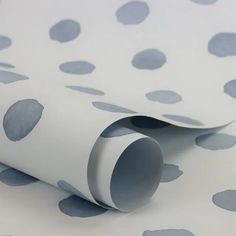 a white and grey polka dot wallpaper with blue circles on the paper, which is rolled up in half