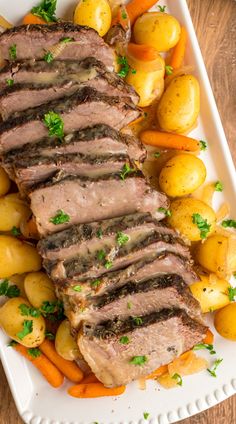 a white plate topped with meat, potatoes and carrots on top of a wooden table