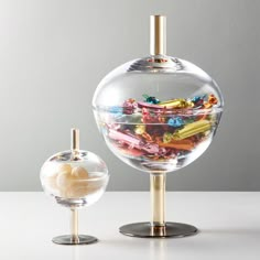 two glass vases sitting on top of a table next to each other with different colored candies in them