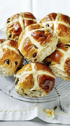 hot cross buns with raisins are on a glass plate, ready to be eaten