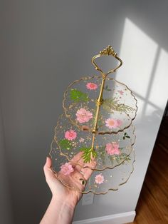 a person holding up a decorative tray with flowers on it and a hook in the middle