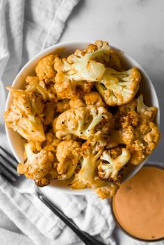 a white bowl filled with cauliflower next to a fork