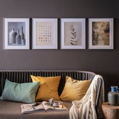 three framed photographs hang above a couch with various pillows and vases on the wall