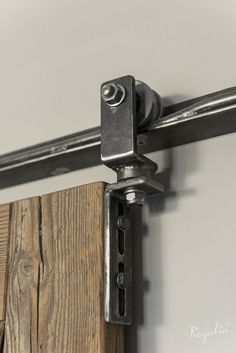 a close up view of a metal handle on a wooden door with white walls in the background