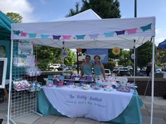 two women standing under a tent selling items