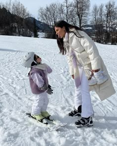 a woman teaching a child how to ski in the snow