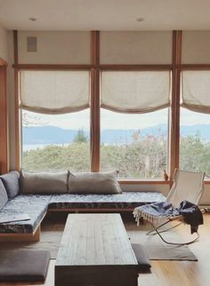 a living room filled with lots of furniture and large windows covered in shades over the mountains