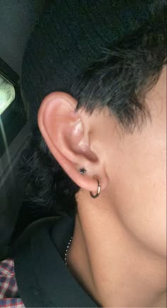 a close up of a person with ear piercings on their ears and an electronic device in the background