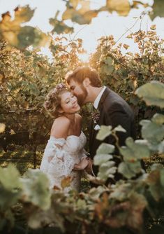 a bride and groom standing in the middle of a vineyard at their wedding day with sun shining through the vines