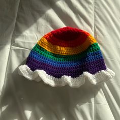 a crocheted rainbow hat laying on top of a white sheet