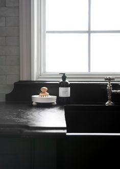 a black counter top with a sink and soap dispenser