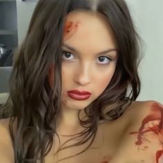 a woman with blood all over her body posing for the camera and looking at the camera