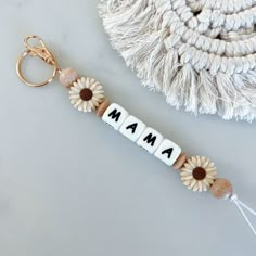 a keychain with the word mama spelled in letters and daisies on it