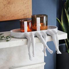 two candles sitting on top of a white shelf