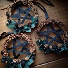 three wicker wreaths with pine cones, berries and leaves hanging on a wooden floor