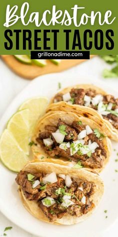 three tacos on a white plate with limes and cilantro in the background