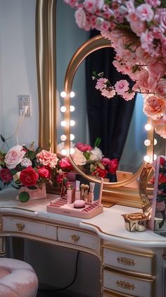 a vanity with pink flowers and lights on it is shown in front of a mirror