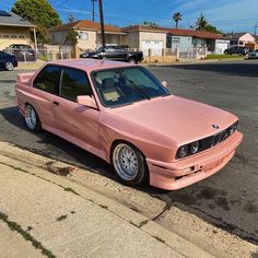 the pink car is parked on the side of the road in front of some houses