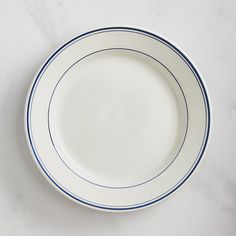 an empty white plate with blue trim on a marble counter top, ready to be used as a serving dish