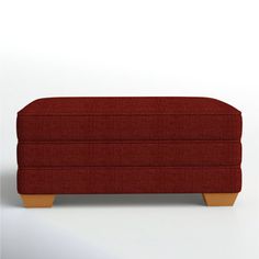 a red couch sitting on top of a white floor next to a wooden legrest