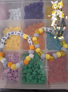 a plastic container filled with lots of different colored beads next to an anime character figurine